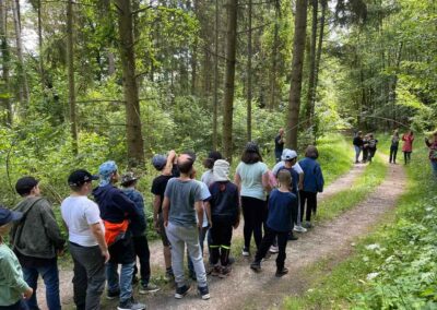 Schülerinnen und Schüler im Wald mit Lehrkräften